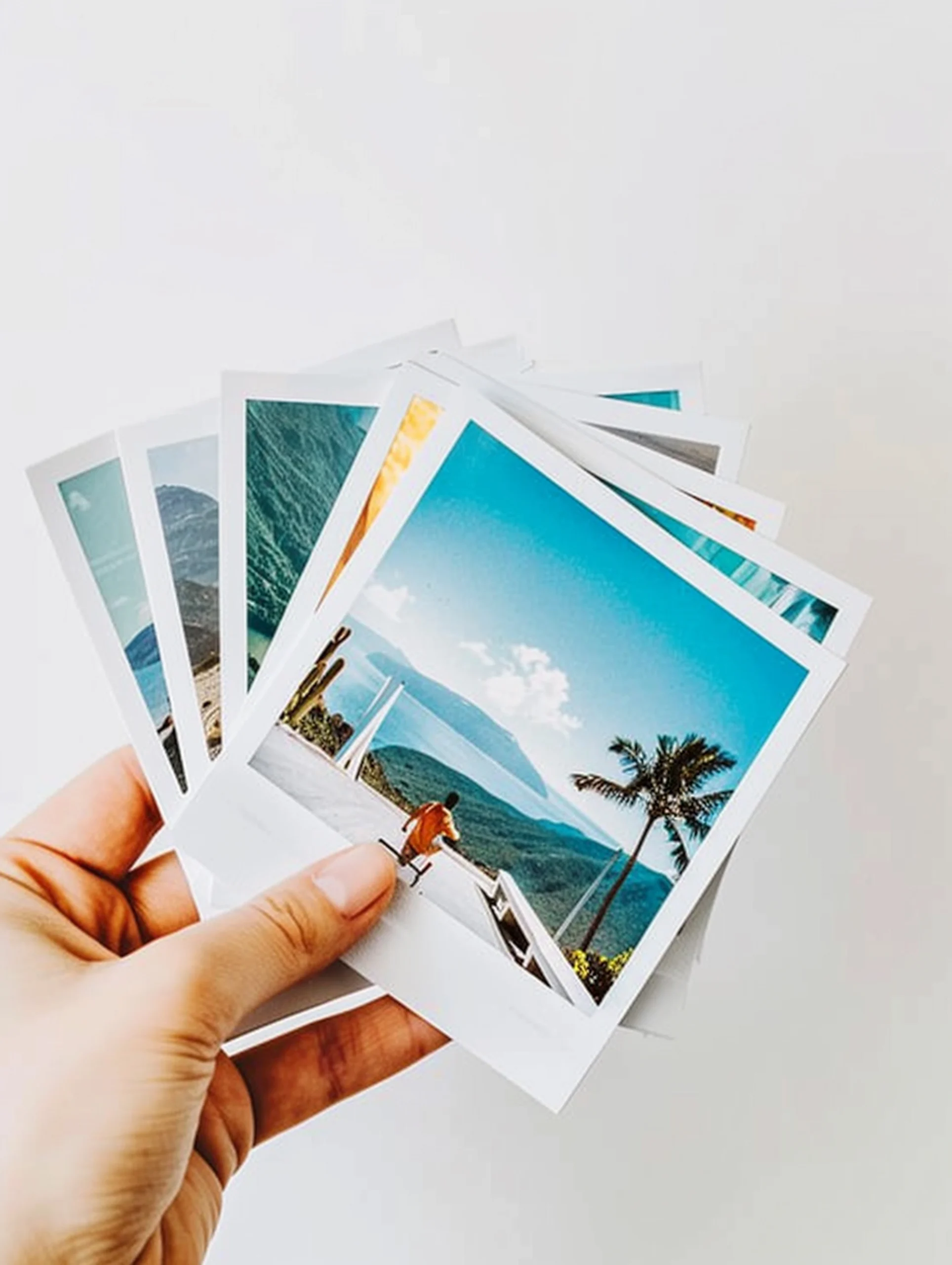alguien-sosteniendo-un-monton-de-polaroids-con-una-vista-del-oceano-generativo-ai photography-hero-section-33